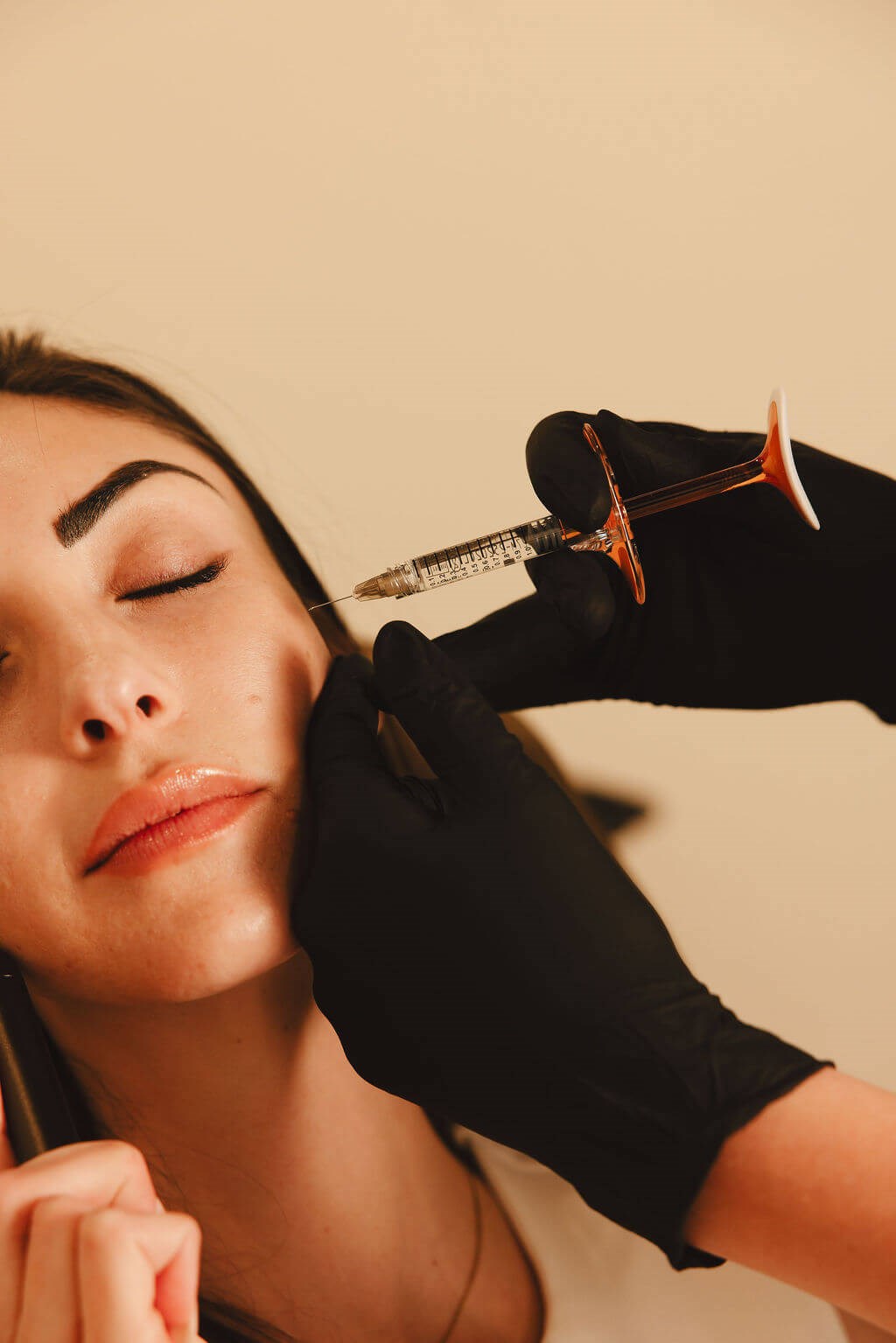 Woman receiving DAXXIFY® injection in cheek for cosmetic enhancement