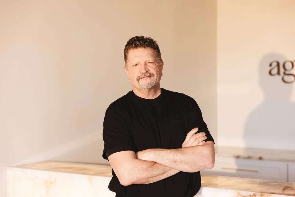 Dr. Daniel Knight, a man with a mustache and goatee, stands with arms crossed.